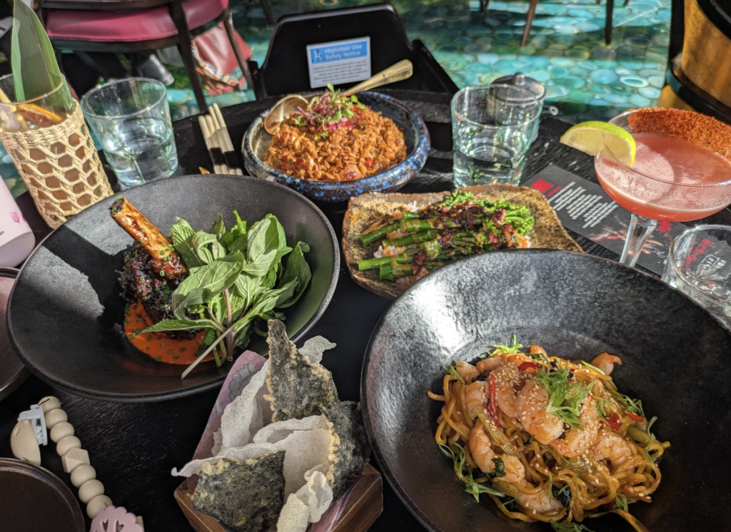 una selezione di piatti, tra cui noodles, costine di manzo e riso, su un tavolo all’Ivy 