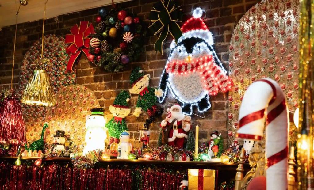 una parete di luci e decorazioni a tema natalizio, tra cui un pinguino natalizio, Babbo Natale e molto altro ancora