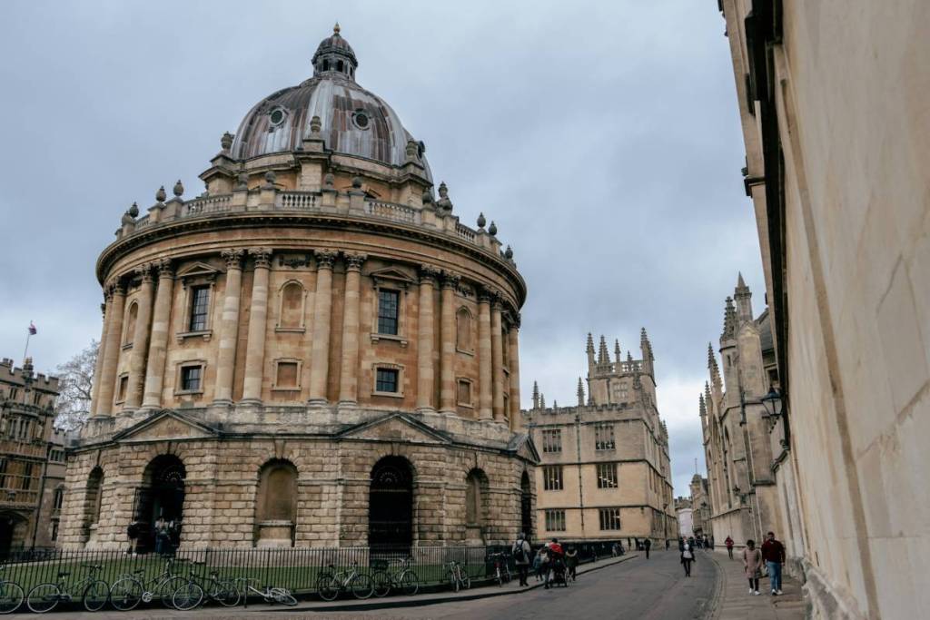 die Außenfassade der Radcliffe Camera in Oxford erklimmen, ein historisches, hoch aufragendes, kuppelförmiges Gebäude, während unten auf den Straßen die Menschen vorbeigehen