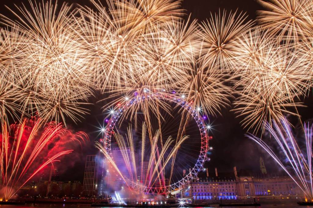 the london new years eve fireworks over london, filling the sky around an illuminated london eye