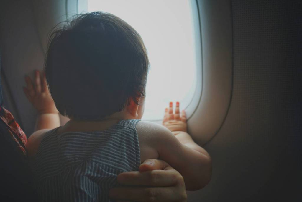 A young baby looking out of a plane window.
