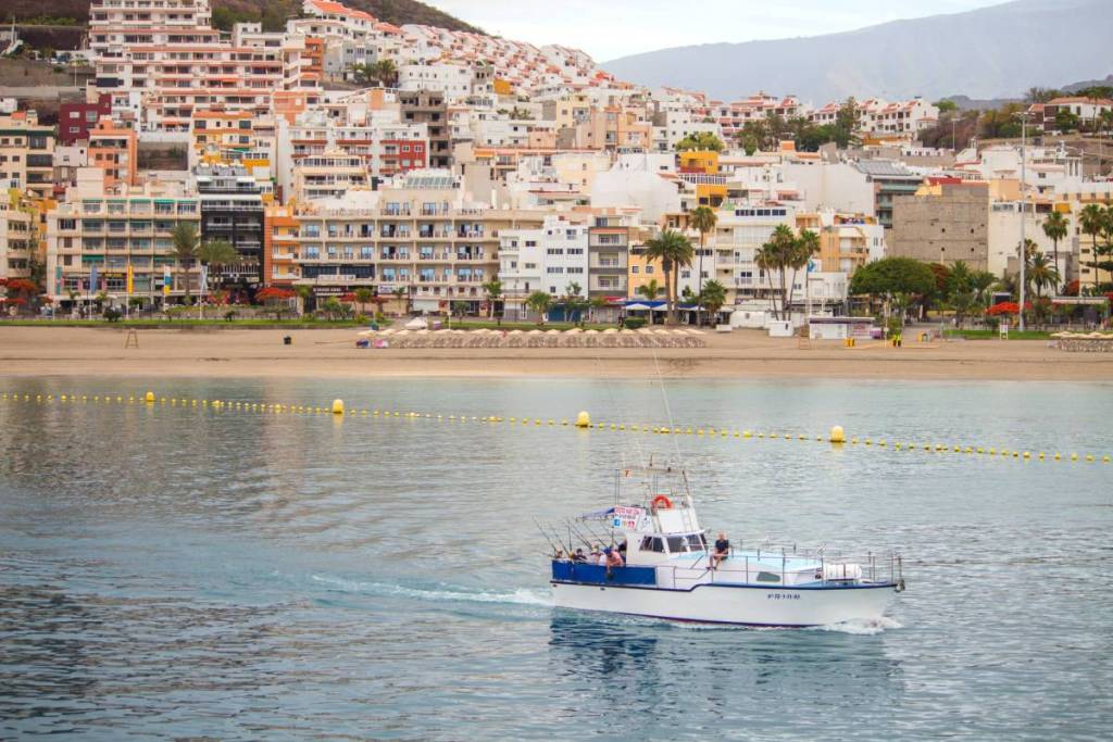 A boat moving through the water with houses and villas in the background