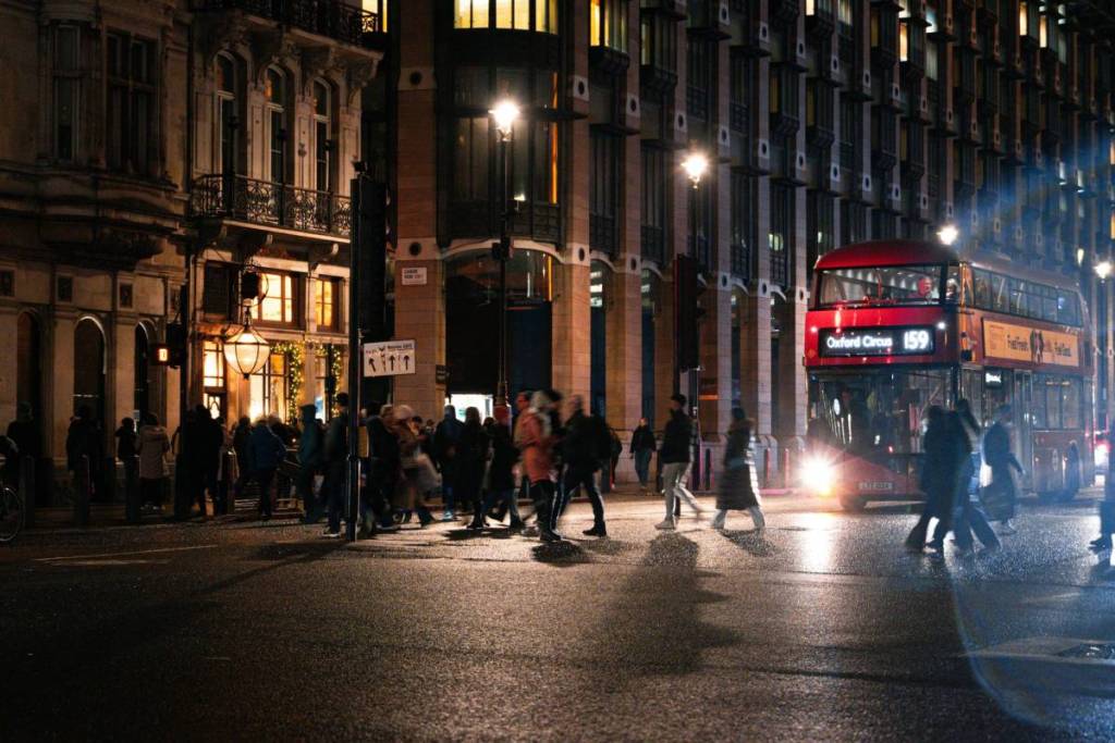 London streets at night with people blurred, walking across the street Credit: Unsplash, Youssef Mubarak