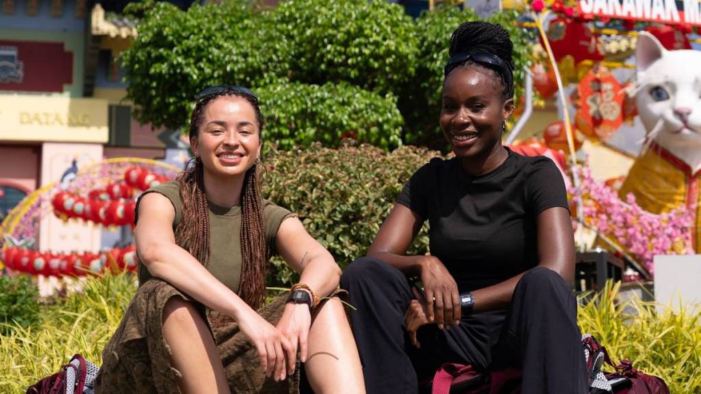 Ella Eyre und ihre Freundin Nana sitzen mit den Armen auf den Knien bei „Race Across the World“