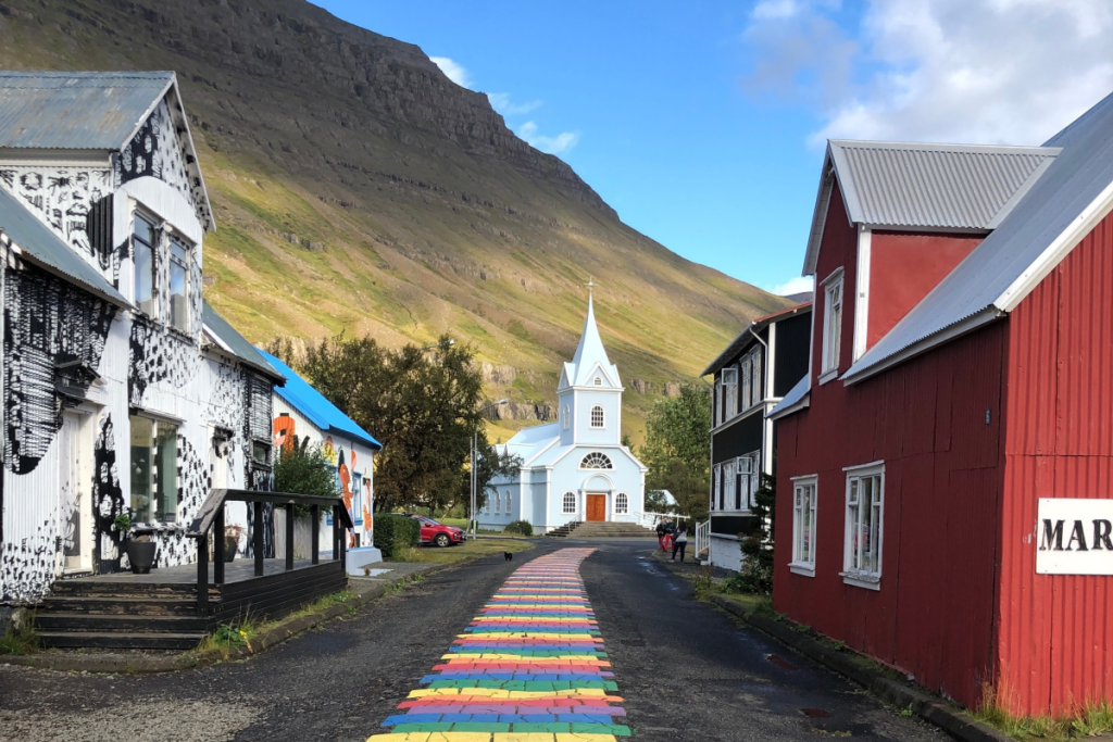 A rainbow path leading to a small blue church in Iceland