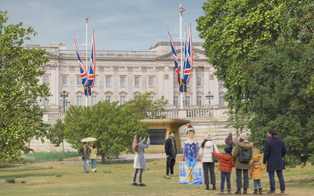 a render of people queueing up in front of, and taking photos of, a scout elf statue in front of buckingham palace