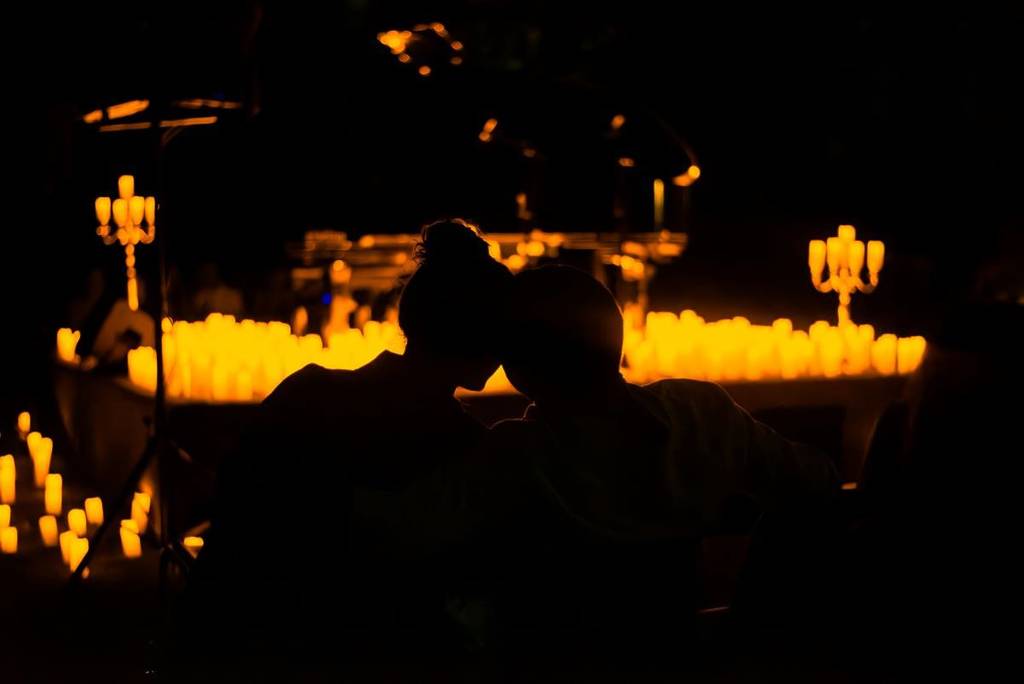 The silhouette of a couple enjoying a Candlelight concert.