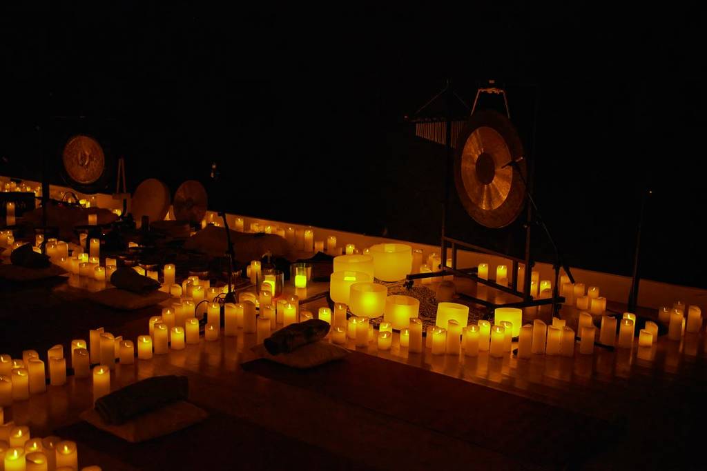 Sound bath instruments set up in a space illuminated by candles.