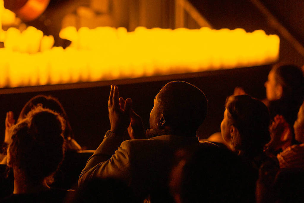 A man clapping at a candlelit concert