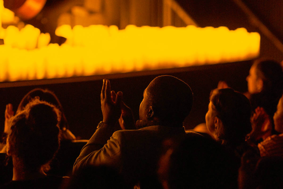A man clapping at a candlelit concert