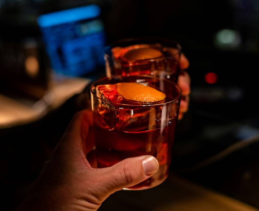 Two cocktail glasses cheersing in a dark bar