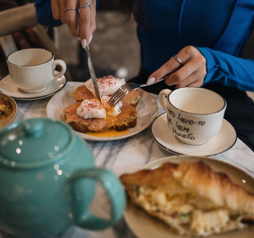 A brunch spread with hands cutting into a piece of French toast