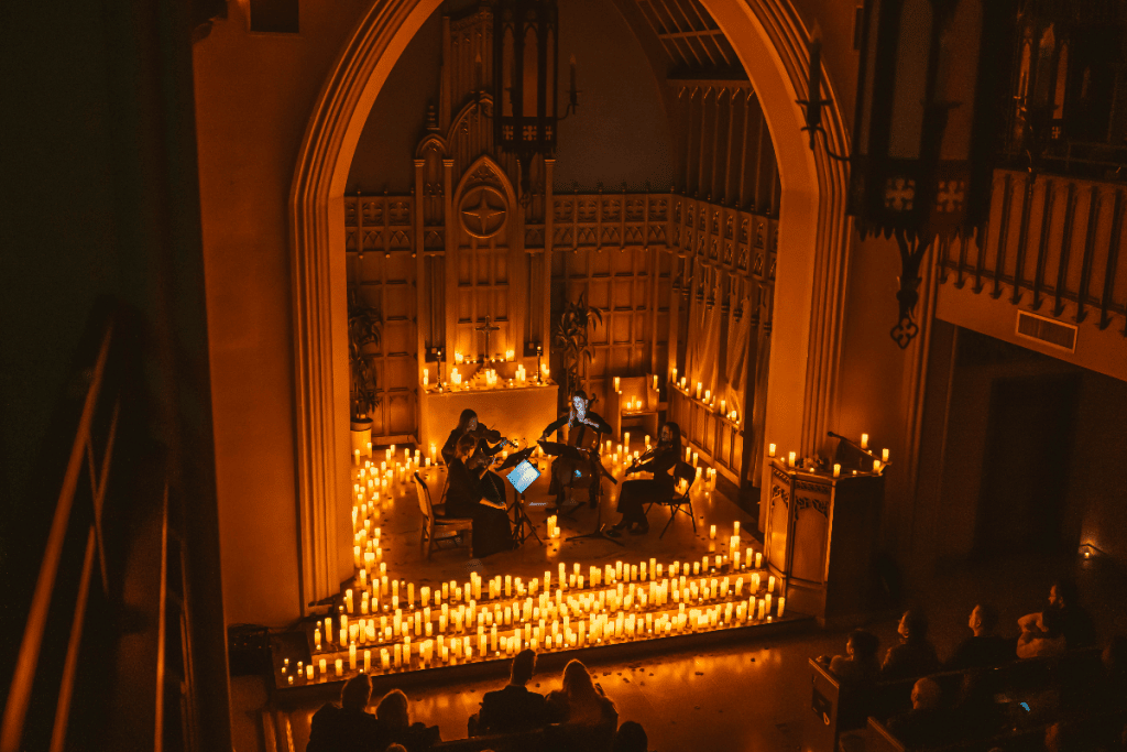 Un cuarteto de cuerda toca en una iglesia rodeada de velas