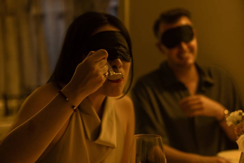 Two diners eating food while blindfolded