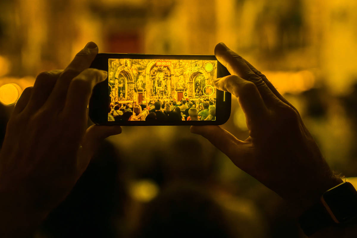 A person takes a photo of a andlelight concrt.