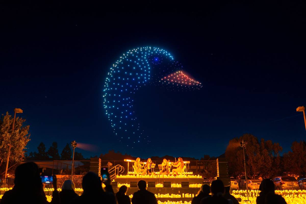 A swan created with drone lights above musicians performing.