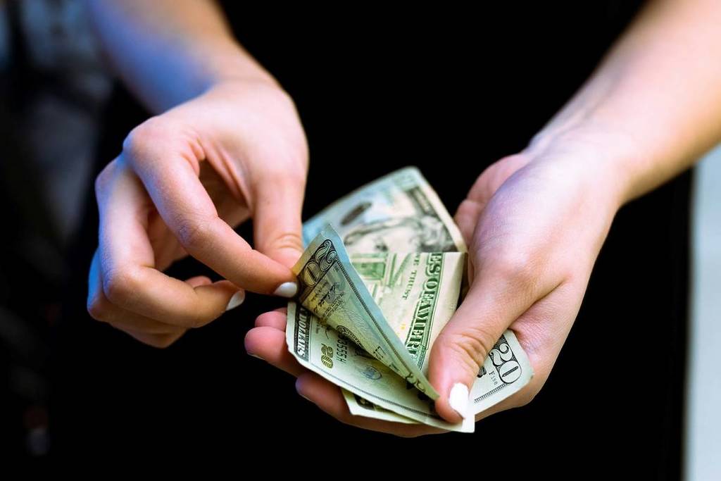 hands counting a stack of American dollar bills