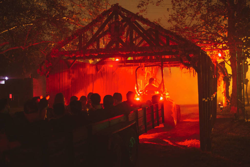 Le Los Angeles Haunted Hayride passe sous une structure à l'éclairage orange.