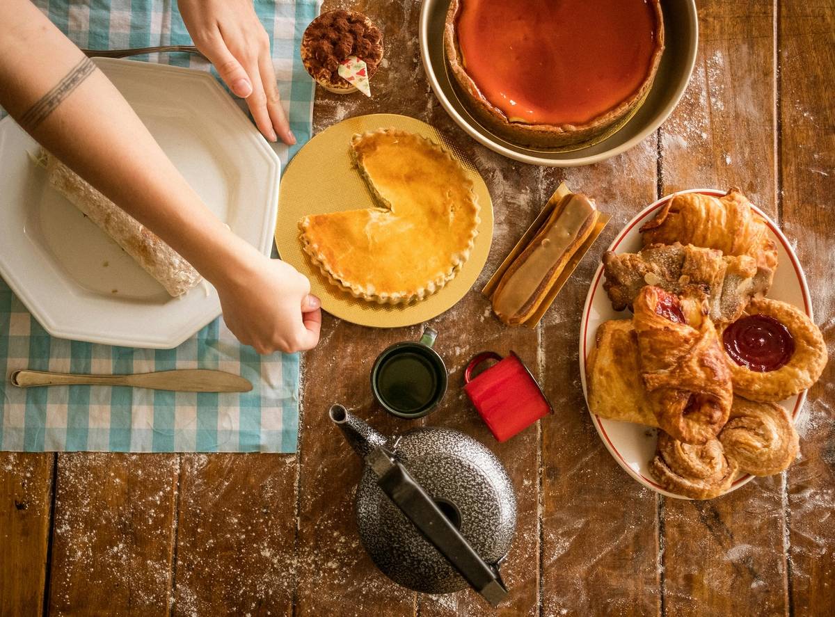 Various pumpkin themed treats sit on a wooden table with a hand adjusting a plate.