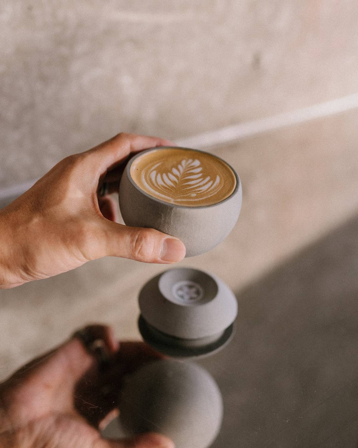 A hand holds up a crafted cup of coffee