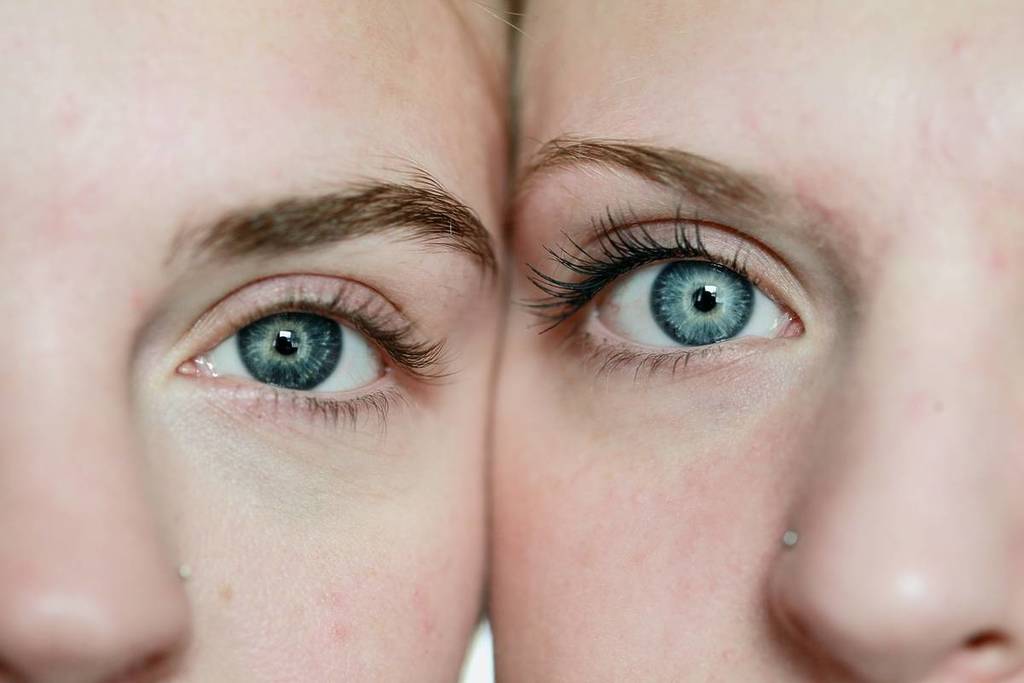 A pair of identical twins stare at the screen with blue eyes.