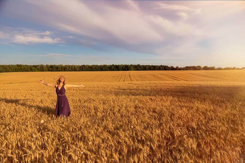 A young woman holding wheat in a field.