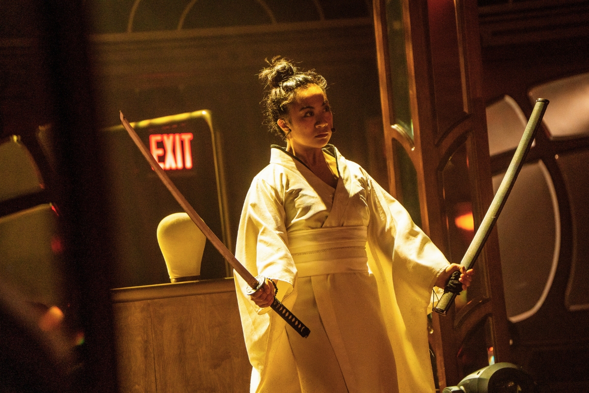 A woman holds katanas onstage