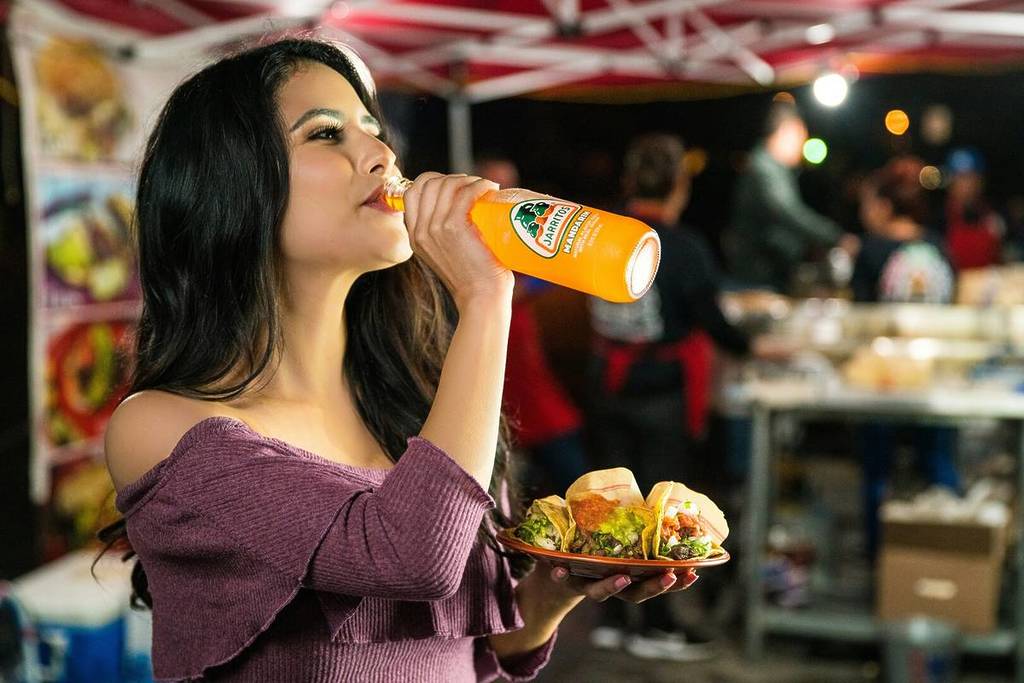 Woman enjoying drink with tacos from a food truck in Los Angeles