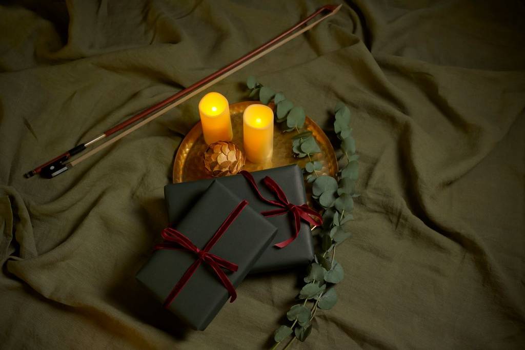 Gifts wrapped in green paper alongside candles at a Candlelight concert.