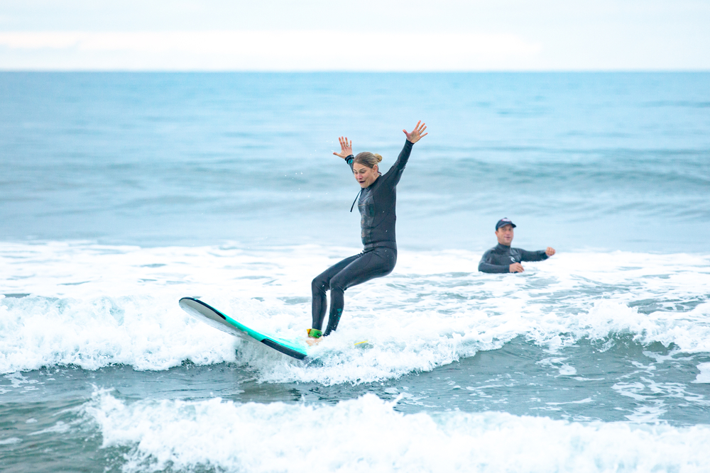 Person enjoying a surfing lesson with their teacher in the water.