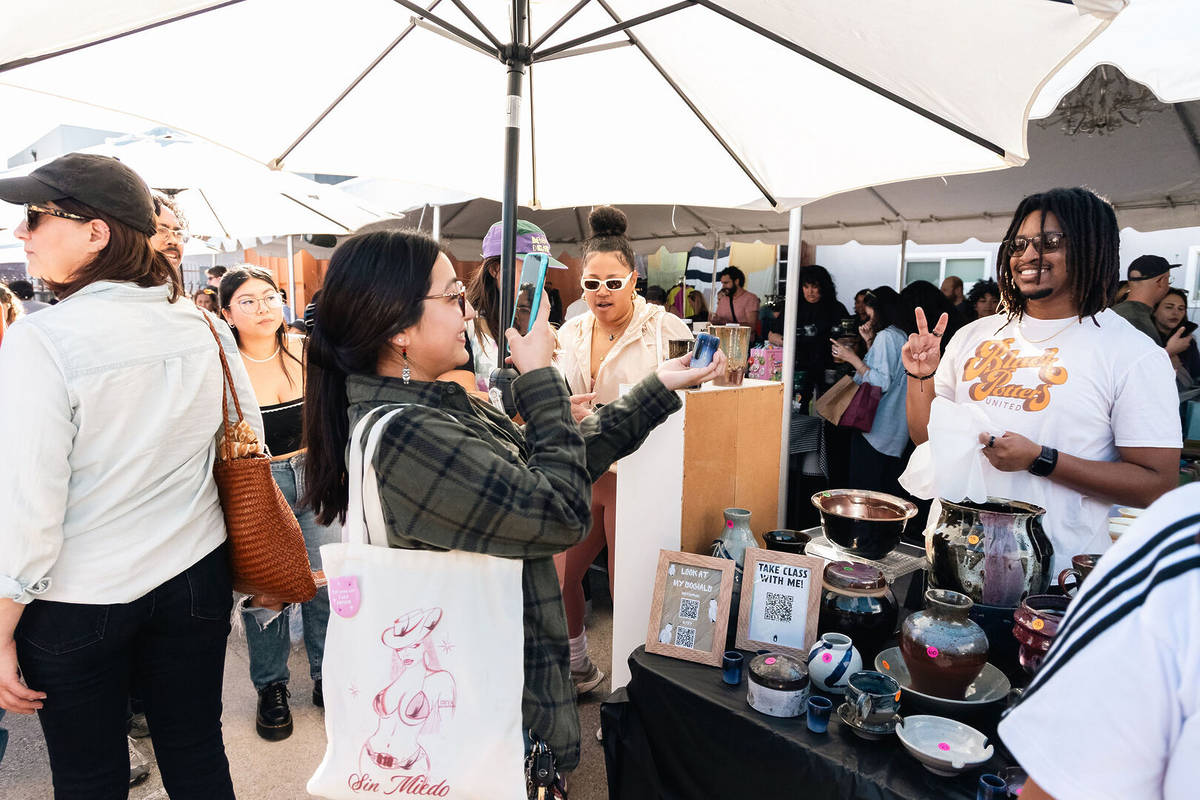 Person taking a picture of ceramics at a busy POT Studio Holiday Market in L.A.
