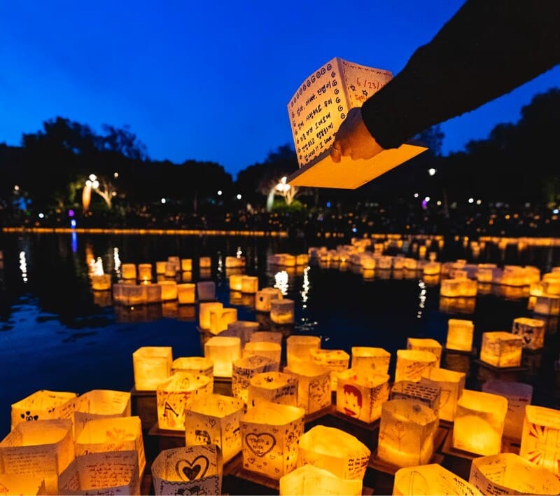 A person releases a water lantern on a body of water after sundown