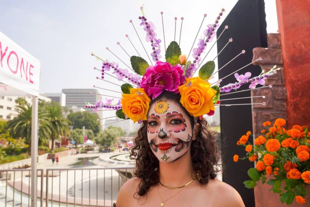 Das Gesicht einer Frau, bemalt als Süßigkeitenschädel für den Día de los Muertos.