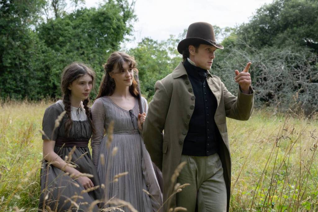 Three characters in the 2026 Sense and Sensibility movie walking in a field.