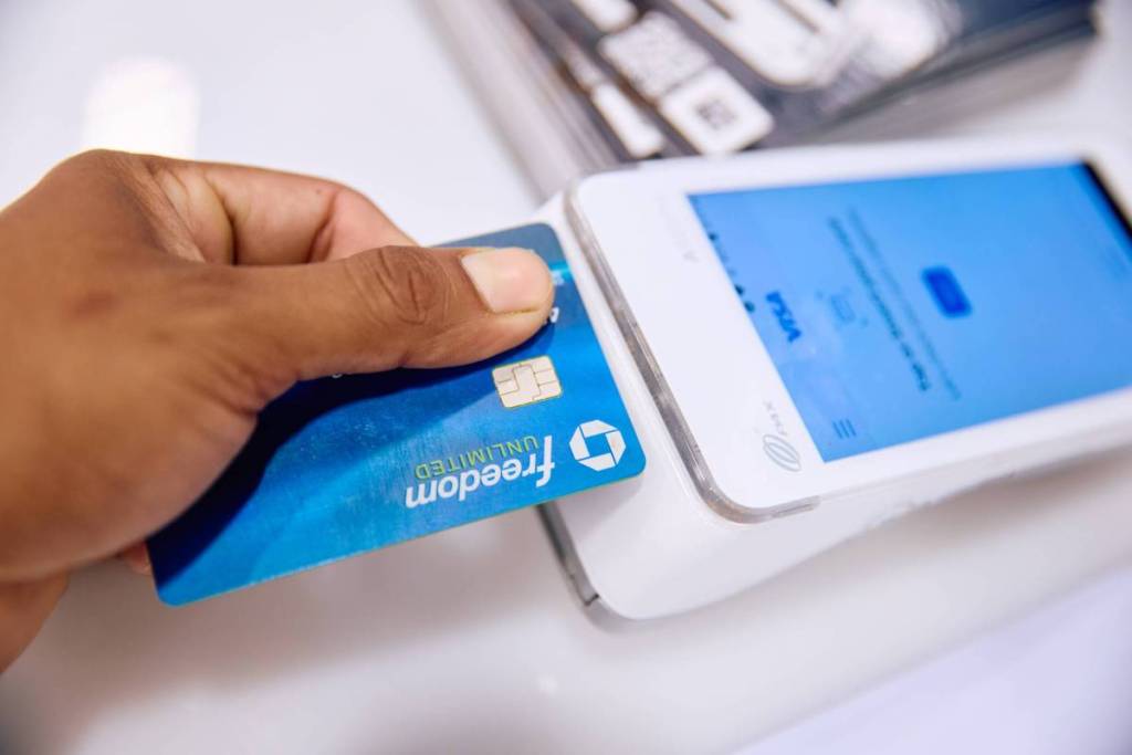 A hand tapping a Chase Freedom card on a POS terminal.