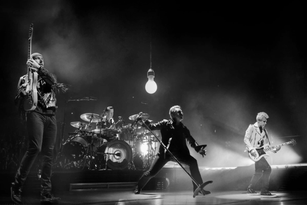 Schwarz-Weiß-Foto von U2 bei einem Auftritt auf der Bühne.