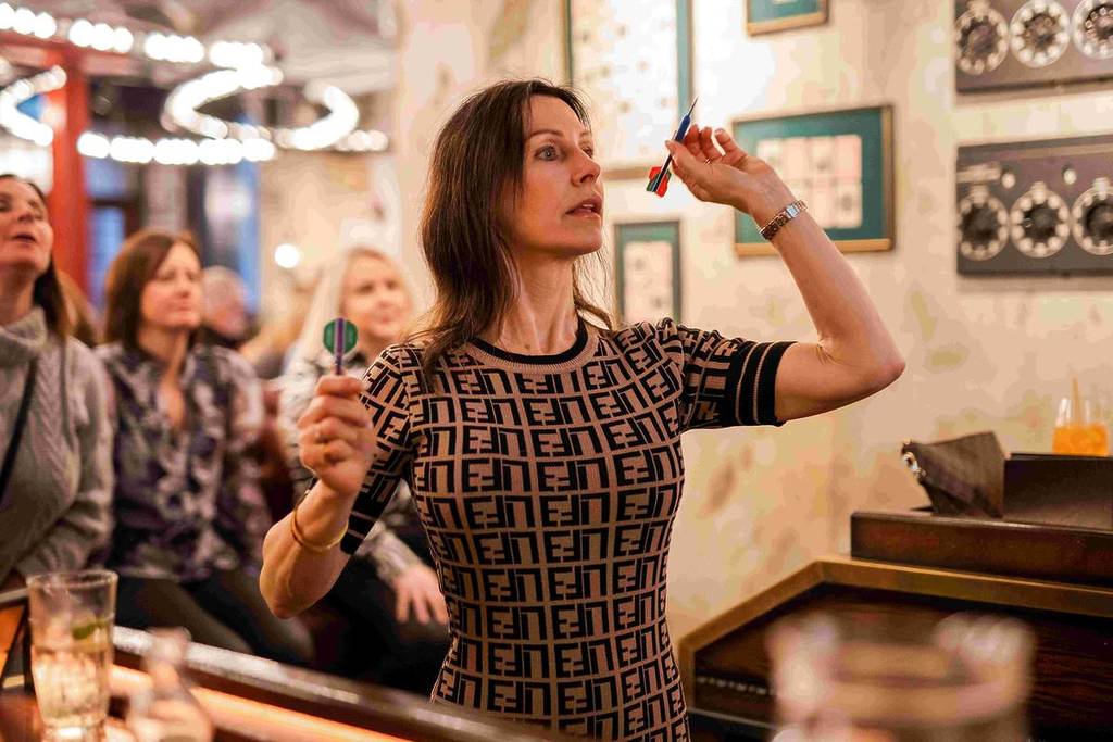 woman taking aim at dartboard at flight club