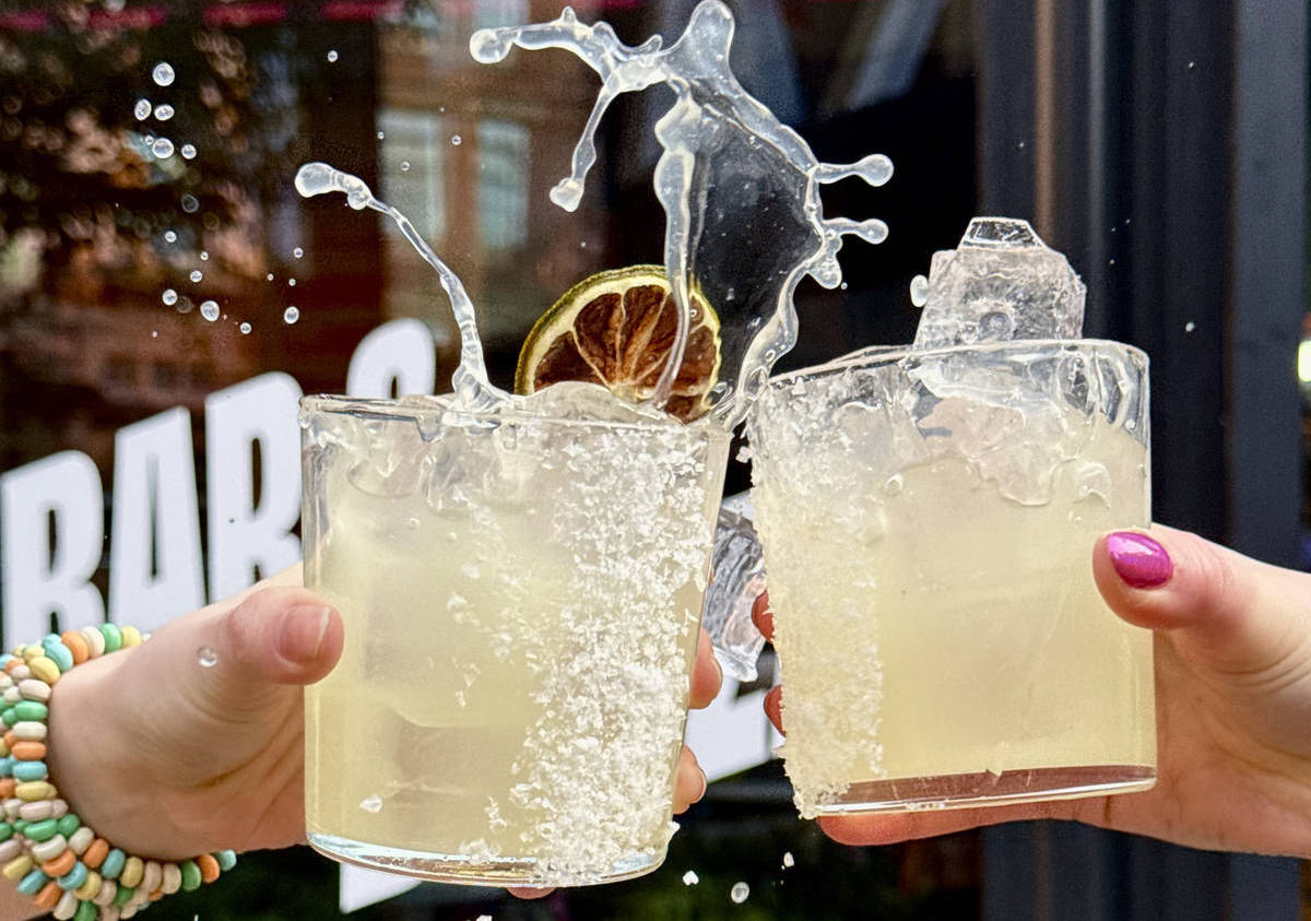 two hands cheersing glasses of classic margaritas outside Nell's restaurant at Kamous, Manchester