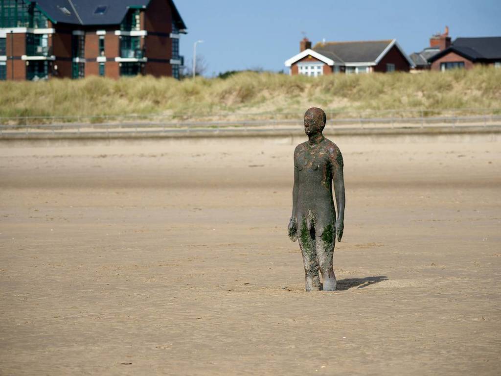statue of a man with legs in sand at crosby beach