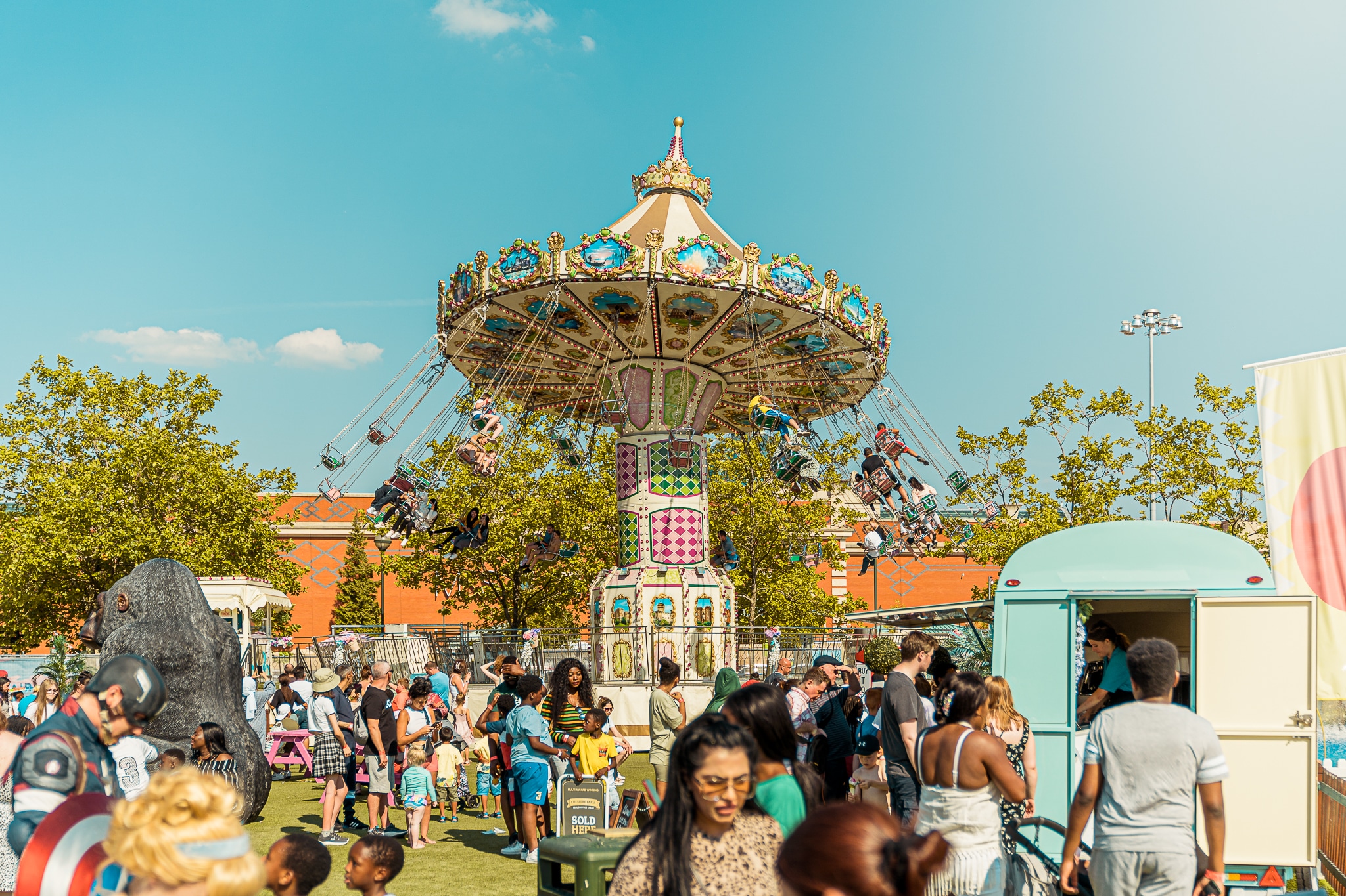 people wandering around fairground with children on swing ride in background