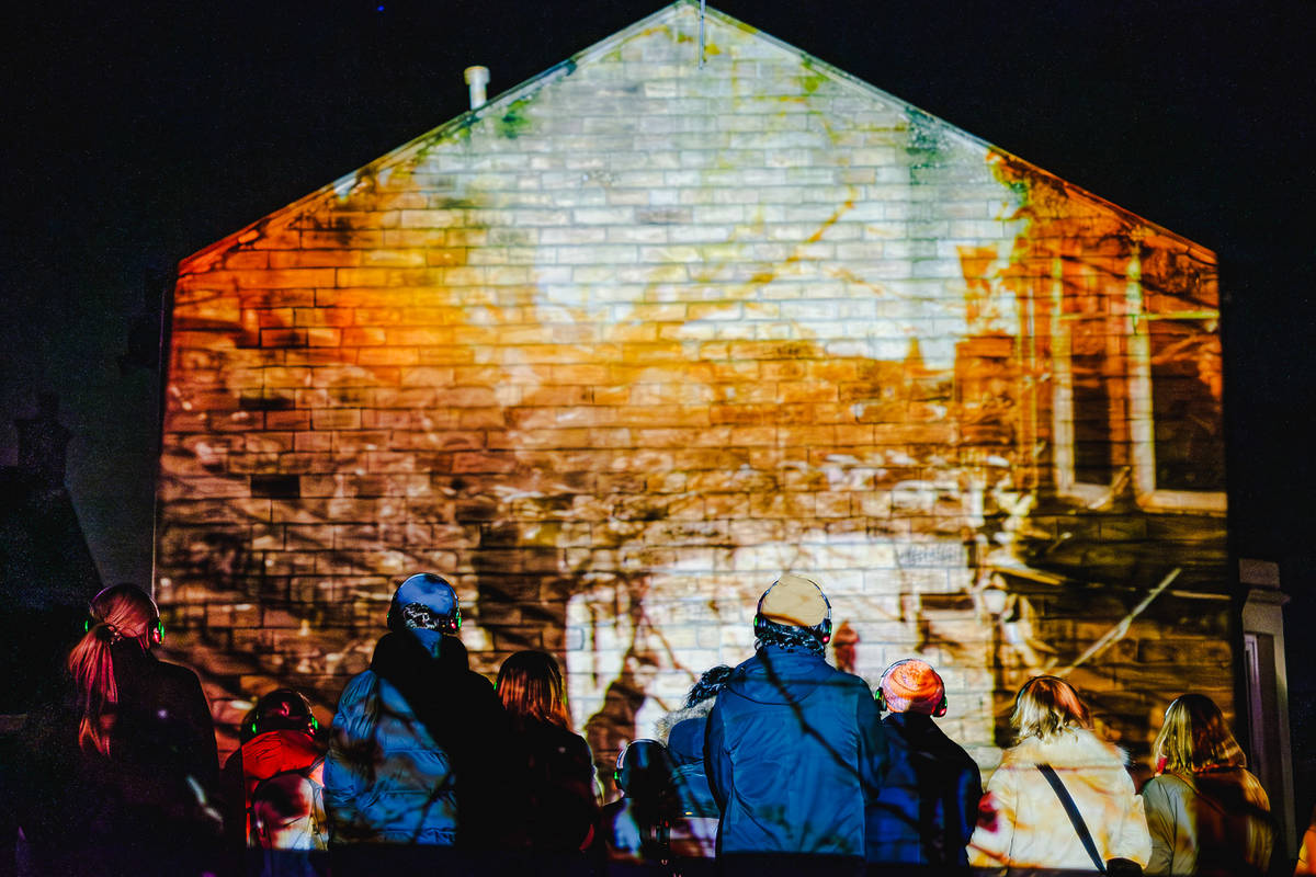 Outdoor image of Stories We Tell with projection mapping on a building.