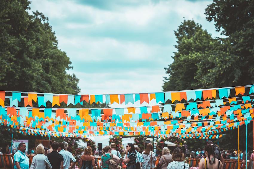 crowd under colourful bunting and blue skies