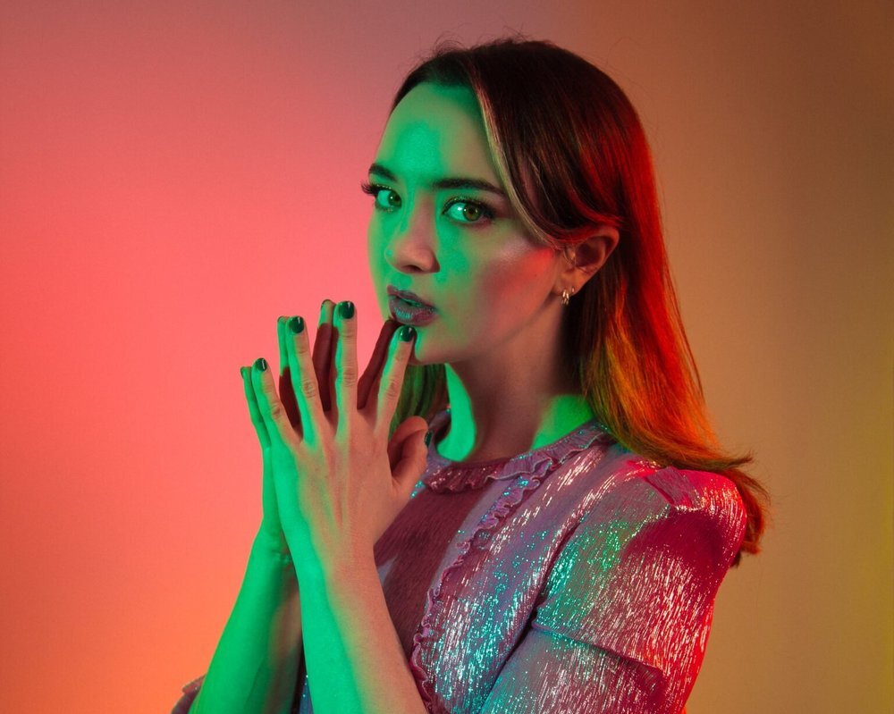 Fern Brady wearing shiny pink jacket under neon light