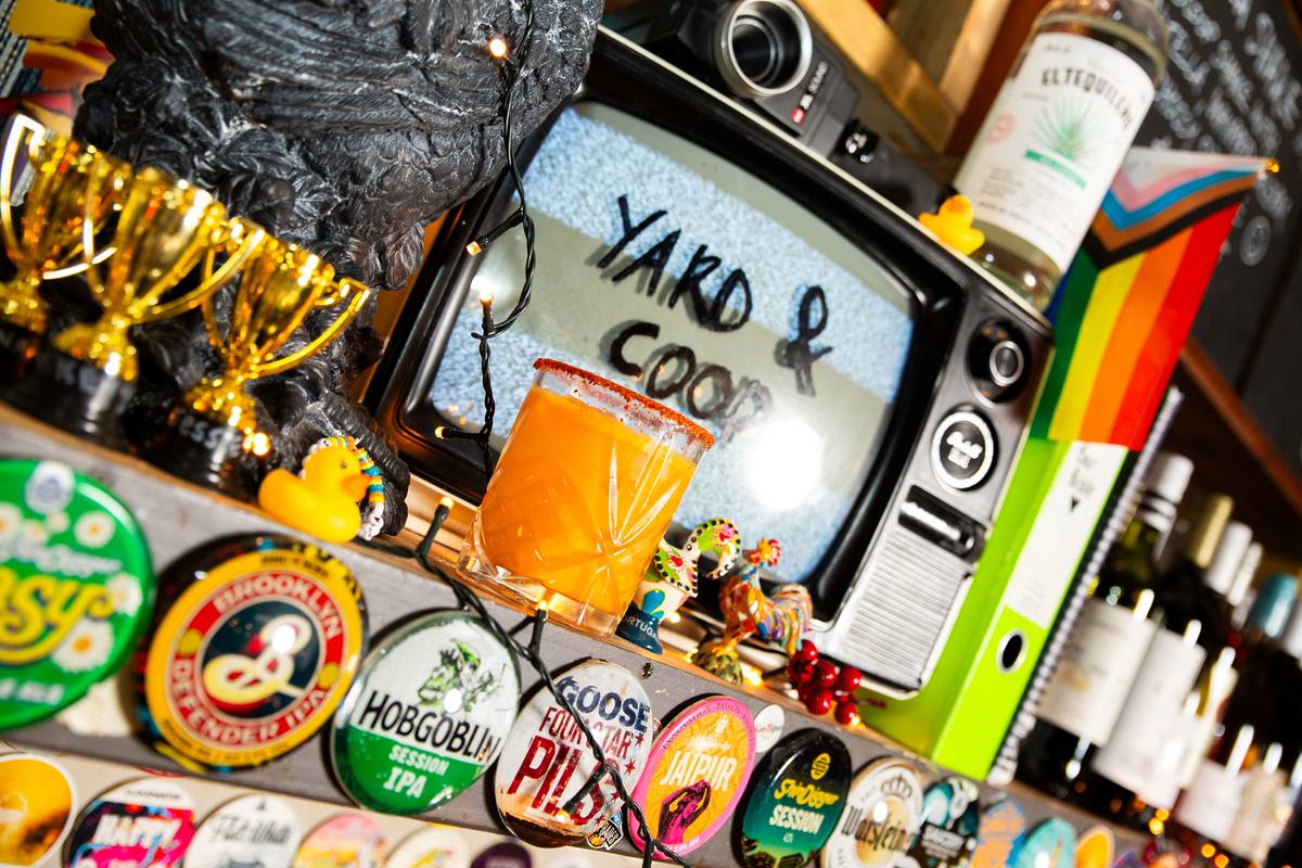 short orange margarita with spicy rim sat on bar next to old tv that reads yard and coop