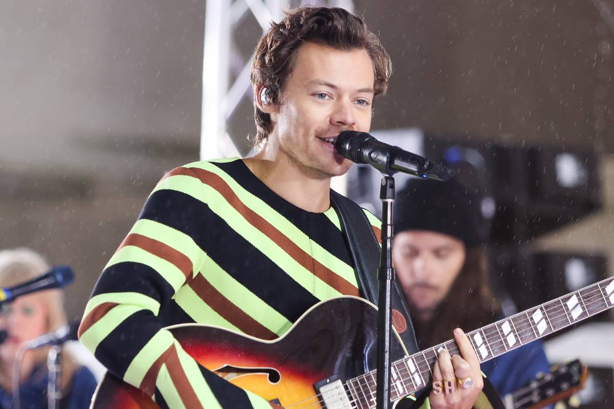 harry-styles-on-stage-performing-in-new-york-with-guitar-and-wearing-green-diagonally-striped-top