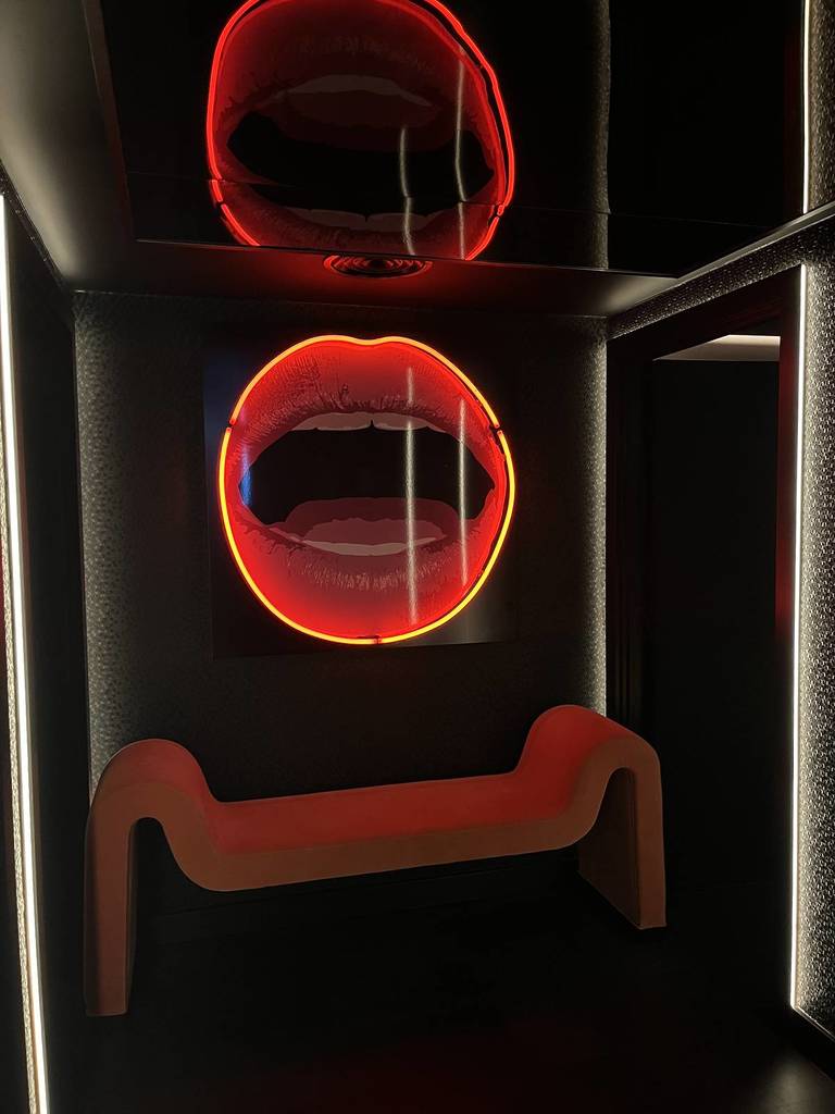 bench outside toilets with neon lip light on wall at maya manchester