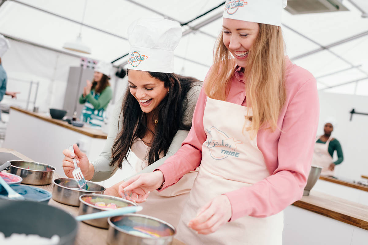 two women baking at the big london bake with white chef hats on, one of the best hen party ideas in manchester