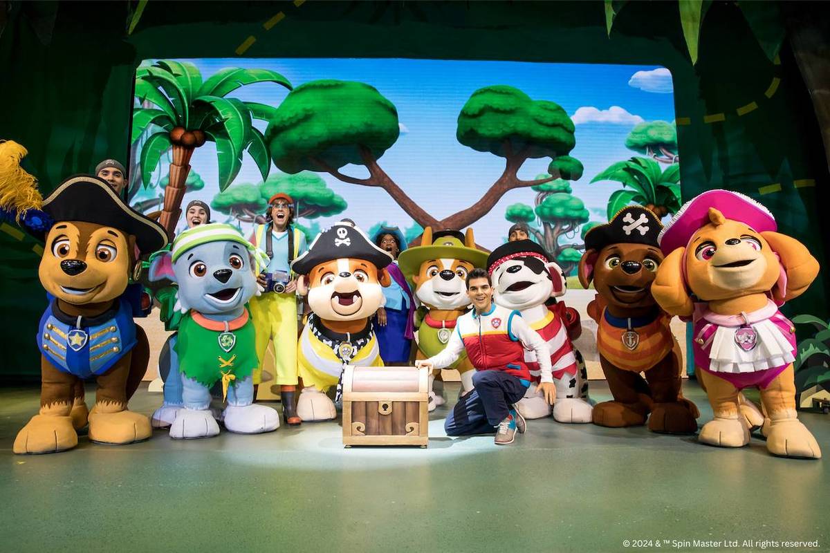 the cast of Paw Patrol live - dressed as their characters in giant dog costumes - cluster around a treasure chest in front of a backdrop of a forest