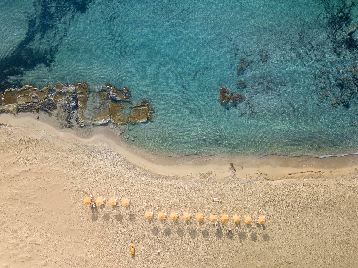 beach with row onf sun beds on sand in crete, greece