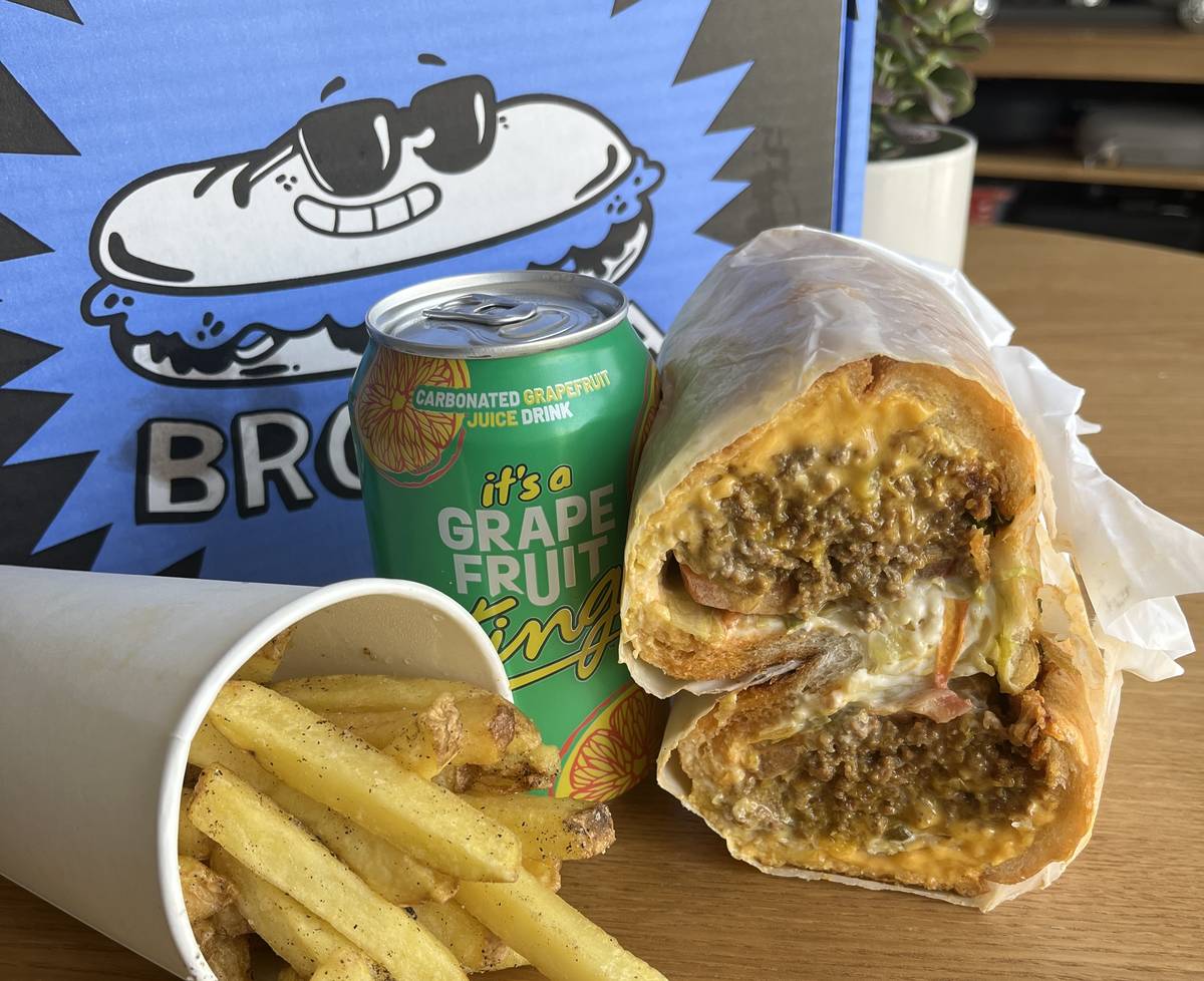 chopped cheese sub next to fries, can of grapefruit soda and shoe box saying brodega